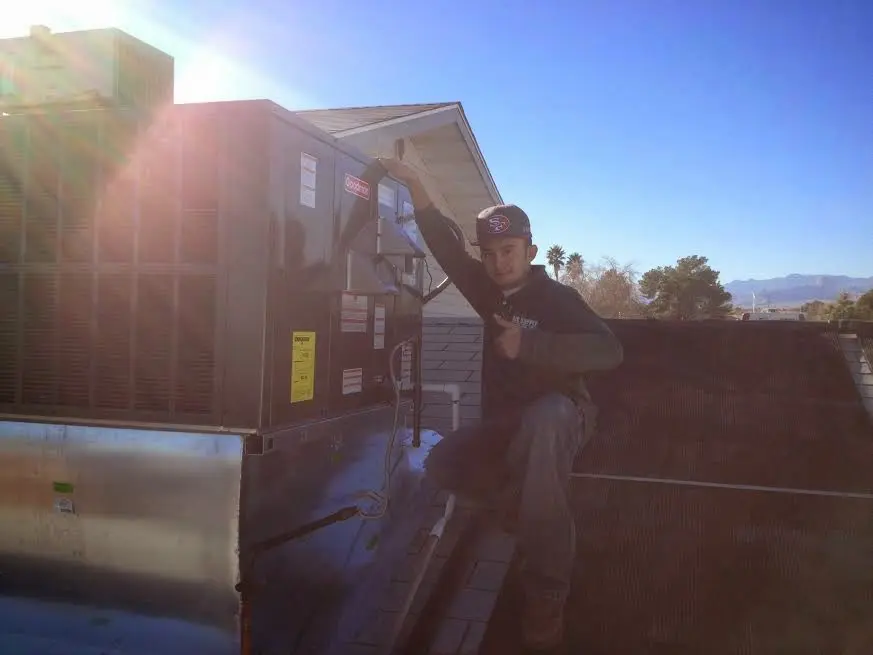 HVAC technician performing Air Duct Repair on a rooftop unit in Kansas City